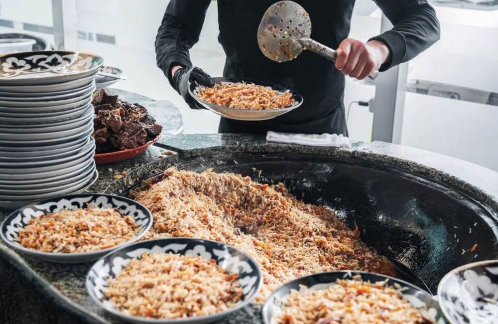 Priprava tradicionalne jedi plov v Uzbekistanu v veliki ponvi
